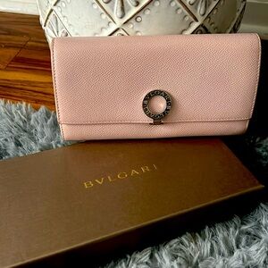 Blush pink folding wallet with a sliver Bvlgari closure clip.